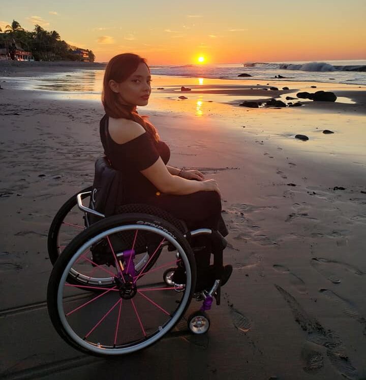 women in wheelchair on the beach during sunset